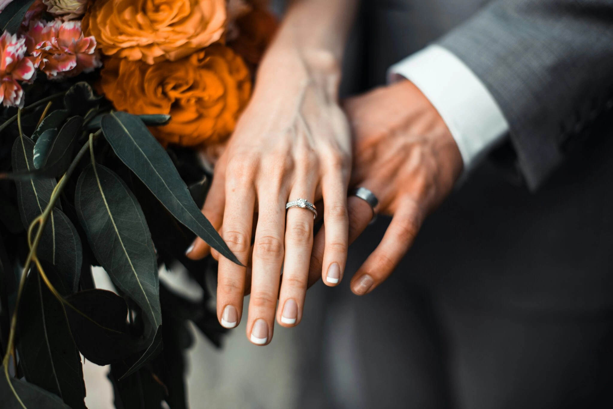 Couple renewing vows outdoors, smiling and holding hands]