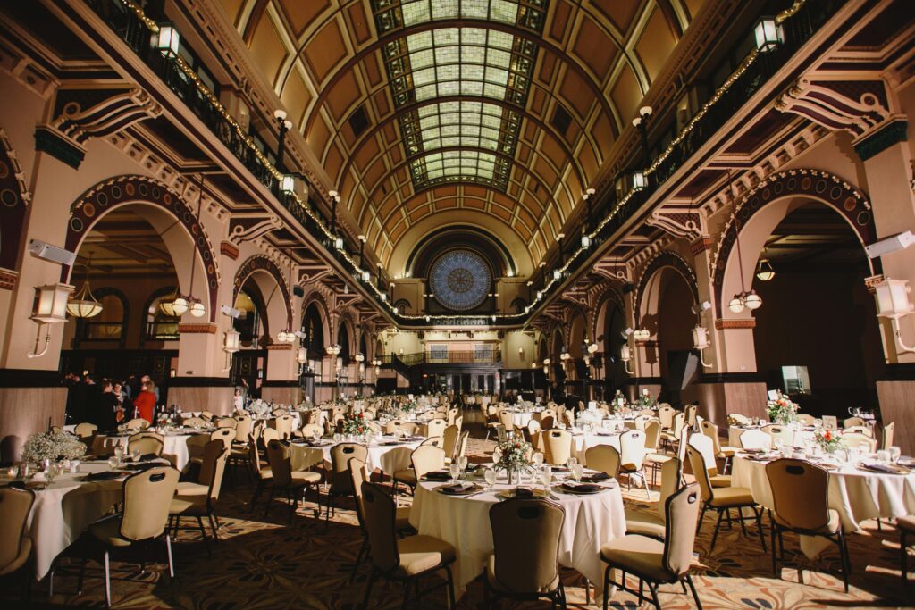 "A grand ballroom with high ceilings, chandeliers, and elegant table settings